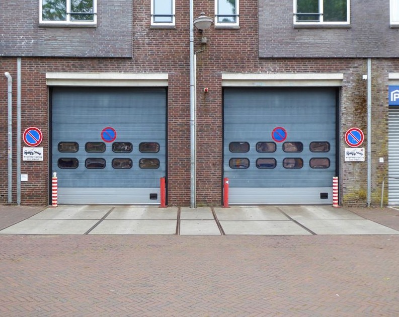 Closed industrial garage doors with no parking signs and brick facade