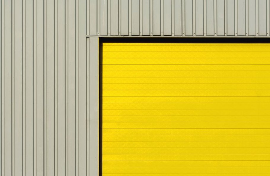 Garage Door Panel Replacement, close-up of a modern garage door with yellow paneling and corrugated grey metal walls
