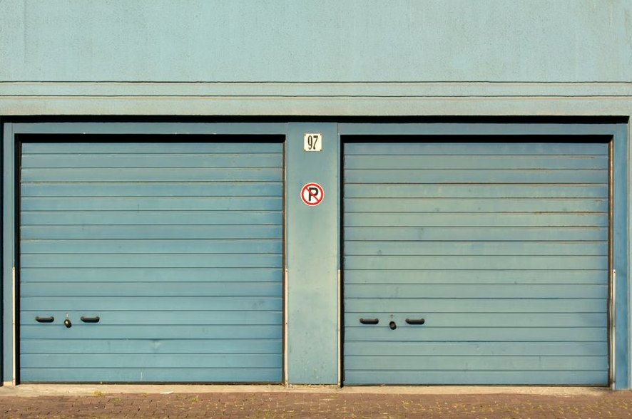Garage Door Roller Replacement, blue garage doors with a no parking sign painted outdoors