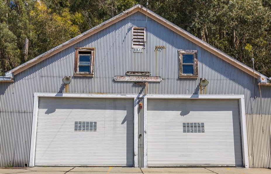 A sunlit vintage metal garage with double doors and rustic charm amidst trees